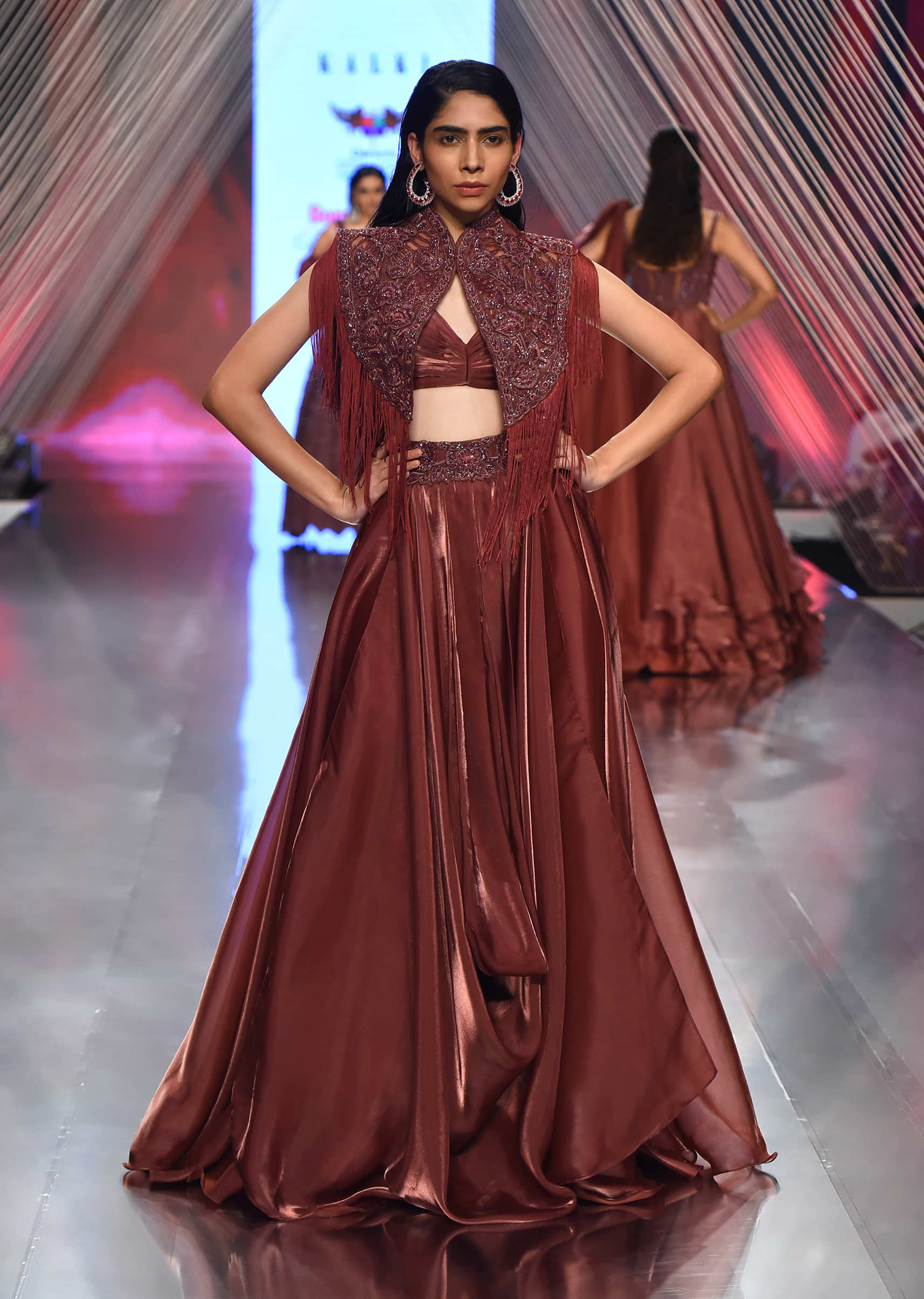 Cherry Organza Lehenga With A Crop Top In Sequins Embroidery, Crop Top Comes In Sleeveless In A V Neckline, Paired With The Matching Fringed Cape
