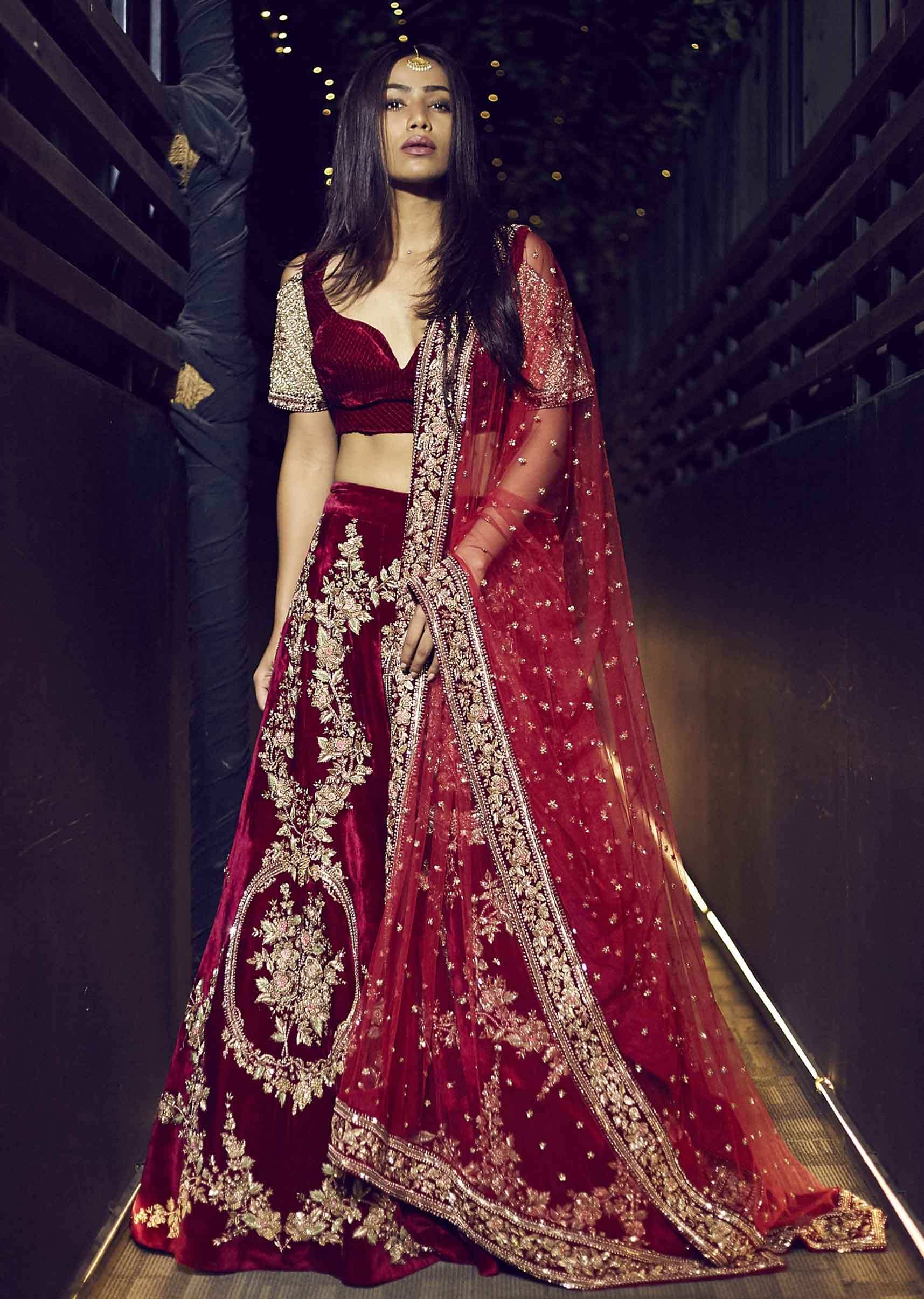 Featuring red velvet lehenga embellished in floral motif embroidery