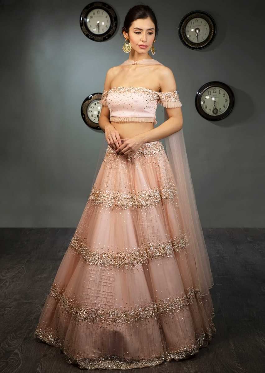 Peach off shoulder crop top paired with matching net skirt in moti and sequins embroidery