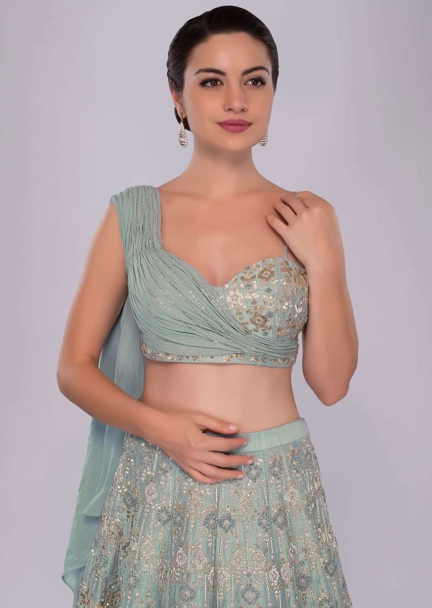 Aqua time blue raw silk lehenga teamed with one side strap bustier with georgette drape