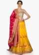 Amber yellow lehenga in floral motif with contrast rani pink dupatta in brocade only on Kalki