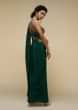 Bottle Green Saree Gown With A Crepe Cowl Drape And Sheer Embroidered Net Bodice With Colorful Resham Flowers  