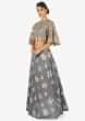 Grey net blouse with fancy cape sleeves paired with resham embroidered skirt