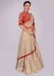Oat tan brocade skirt with attached organza dupatta and red raw silk embroidered blouse