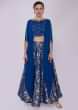 Royal blue brocade lehenga paired with long fancy crop top with fancy cape 