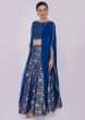 Royal blue brocade lehenga paired with long fancy crop top with fancy cape 