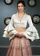 White satin blouse with layered frill sleeves paired with peach  net skirt in moti and sequins  embroidery
