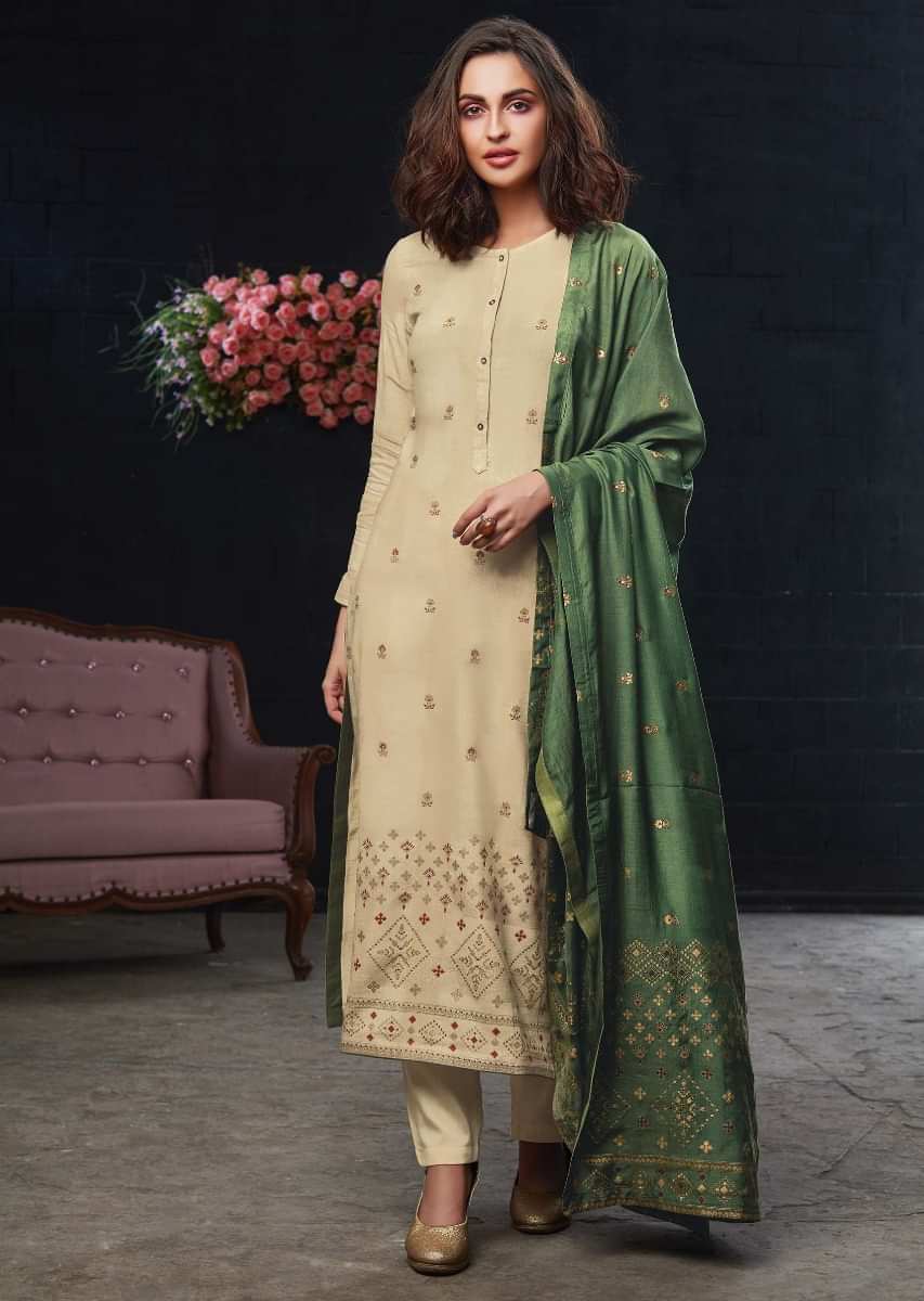 Featuring beige unstitched suit in floral motif foil printed butti with rama green dupatta
