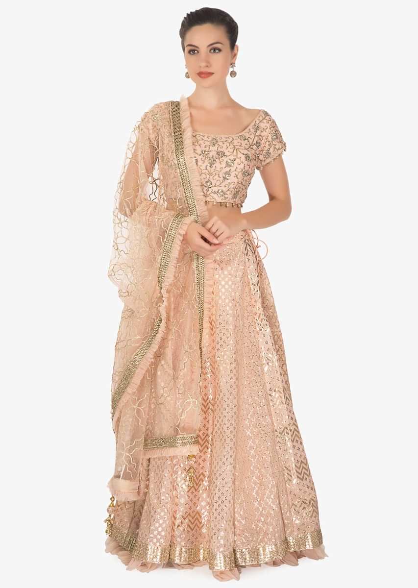 Featuring Peach silk blouse and weaved lehenga paired with a net dupatta only on Kalki