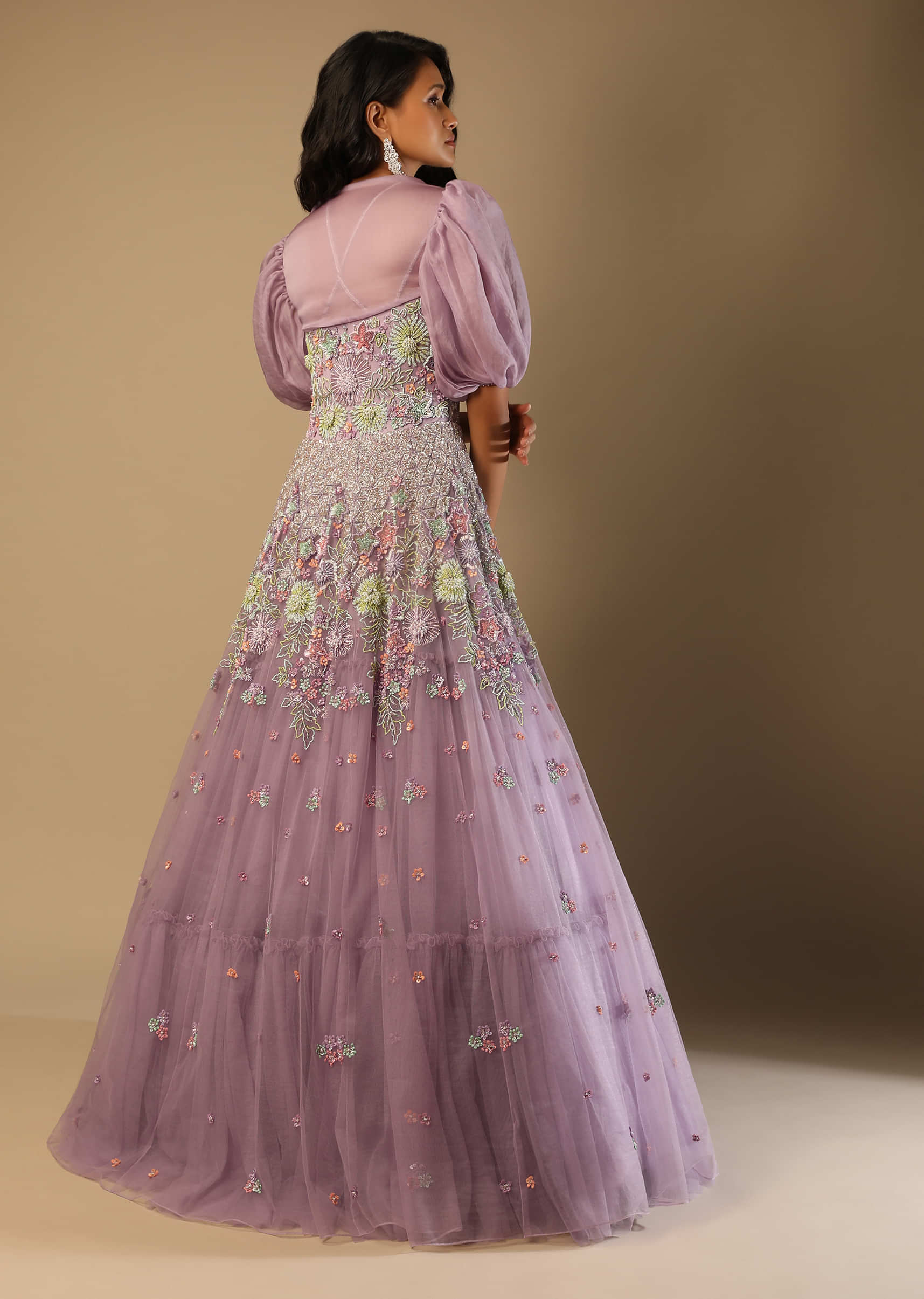 Lilac Mauve Gown In Net With Multi Colored Beads Embroidered Floral Motifs And A Puff Sleeves Organza Shrug  