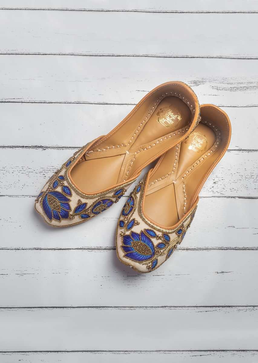 Off White Juttis In Linen With Blue Resham Work, Gold Beads And A Hit Of Swarovski By Vareli Bafna