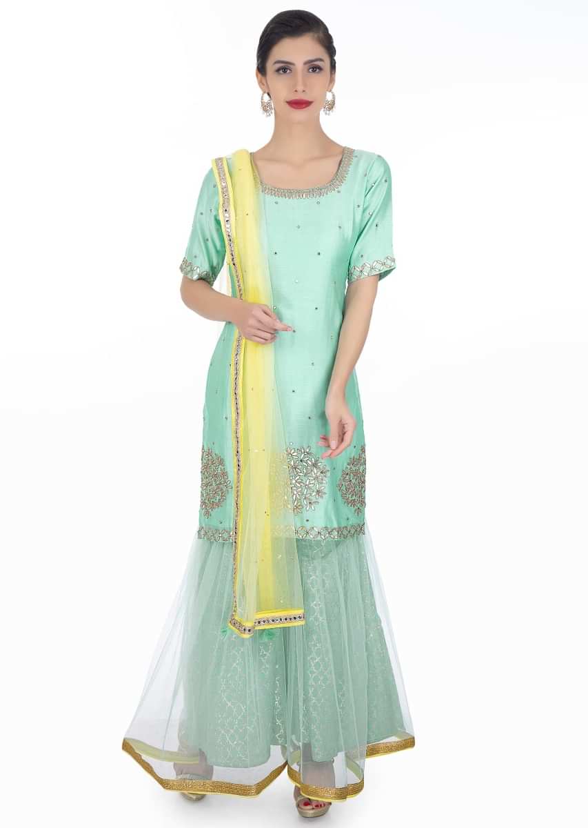 Mint blue embroidered silk suit paired with brocade lehenga in net lining and a contrasting yellow net dupatta 