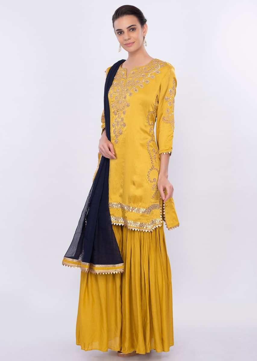Mustard embroidered sharara suit set with contrasting navy blue dupatta only on Kalki