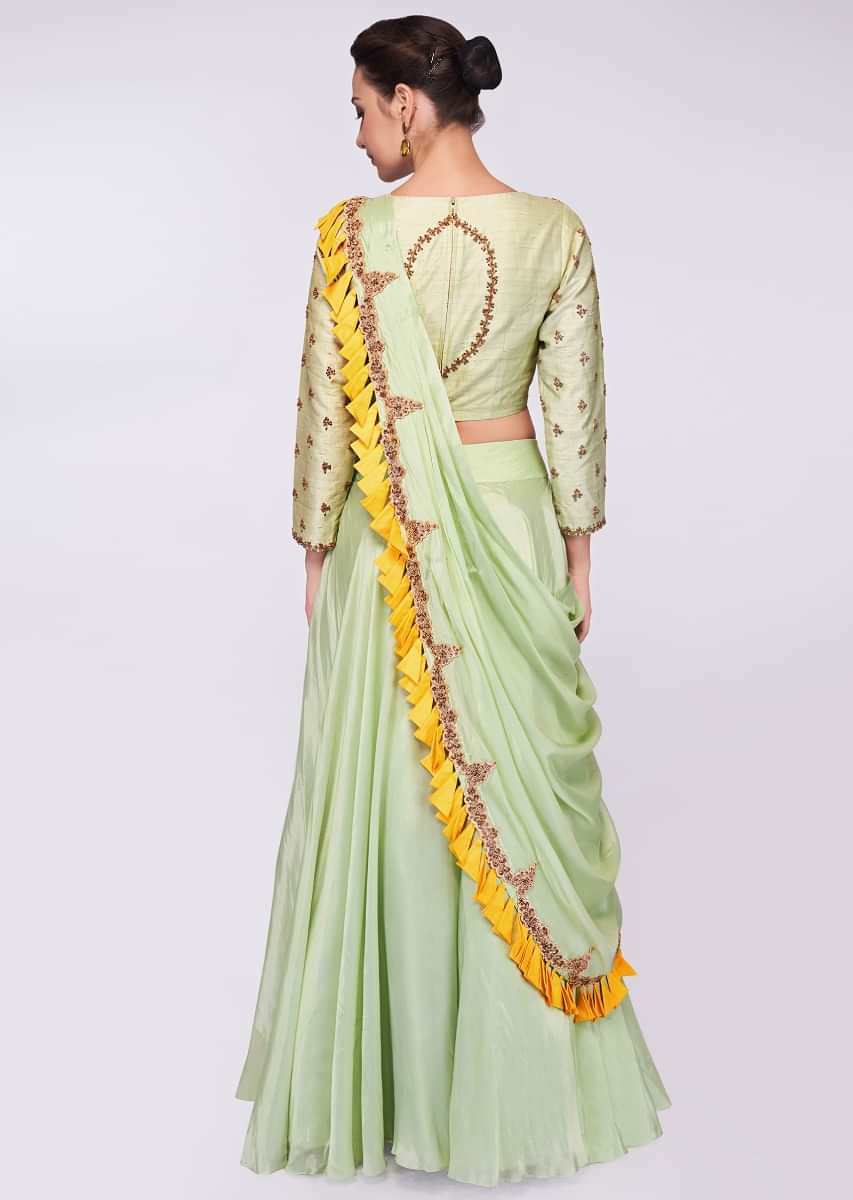 Pista green raw silk blouse in embroidery and butti paired with matching organza skirt and wrap around 