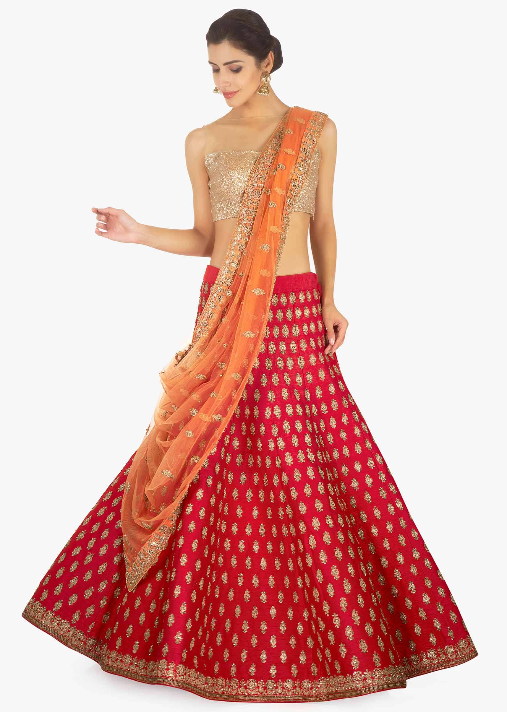 Red raw silk lehenga and blouse paired with a contrasting peach net dupatta