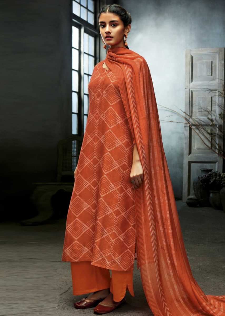 Unstitched suit featuring in fire orange with geometric printed pattern and sequin work