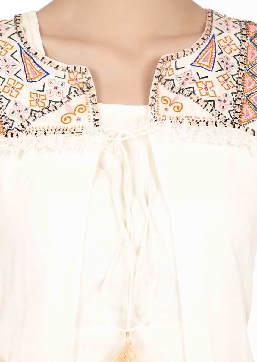 White jump suit paired with an asymmetric embroidered jacket 